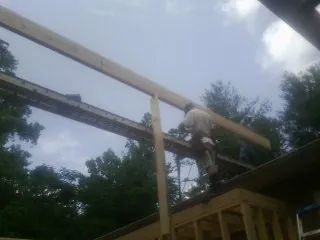 Carpenter setting a ridge beam over a new addition frame — Ice Dam Removal by Roofing Brothers in Piffard