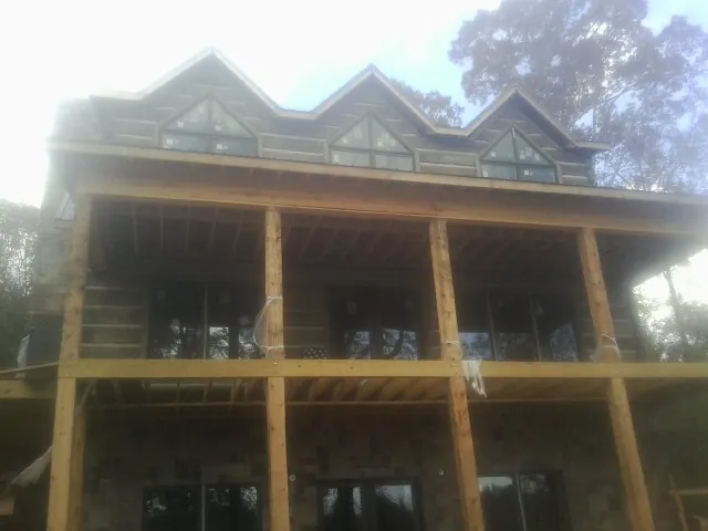 Dormers and porch framing on a large log home under construction — Roof Coating work by our crew in Piffard