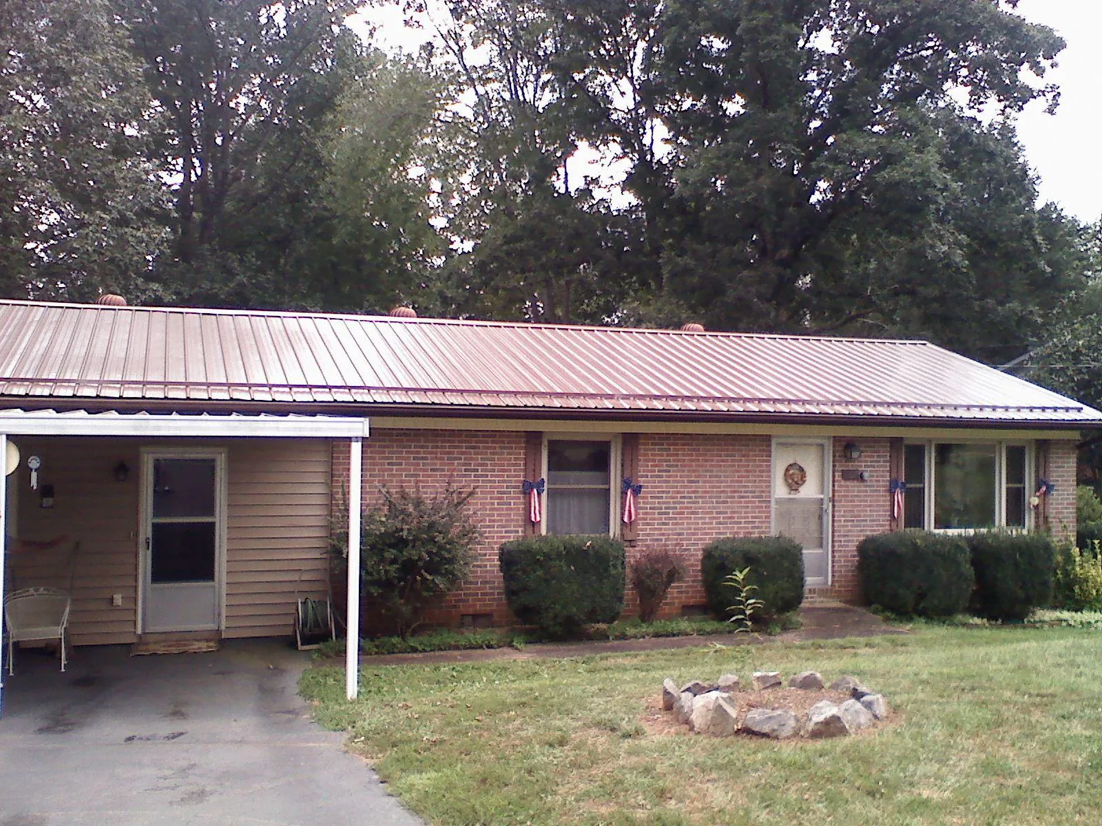 Bronze metal roof and carport on a brick ranch home — Roof Repair work by our crew in Piffard