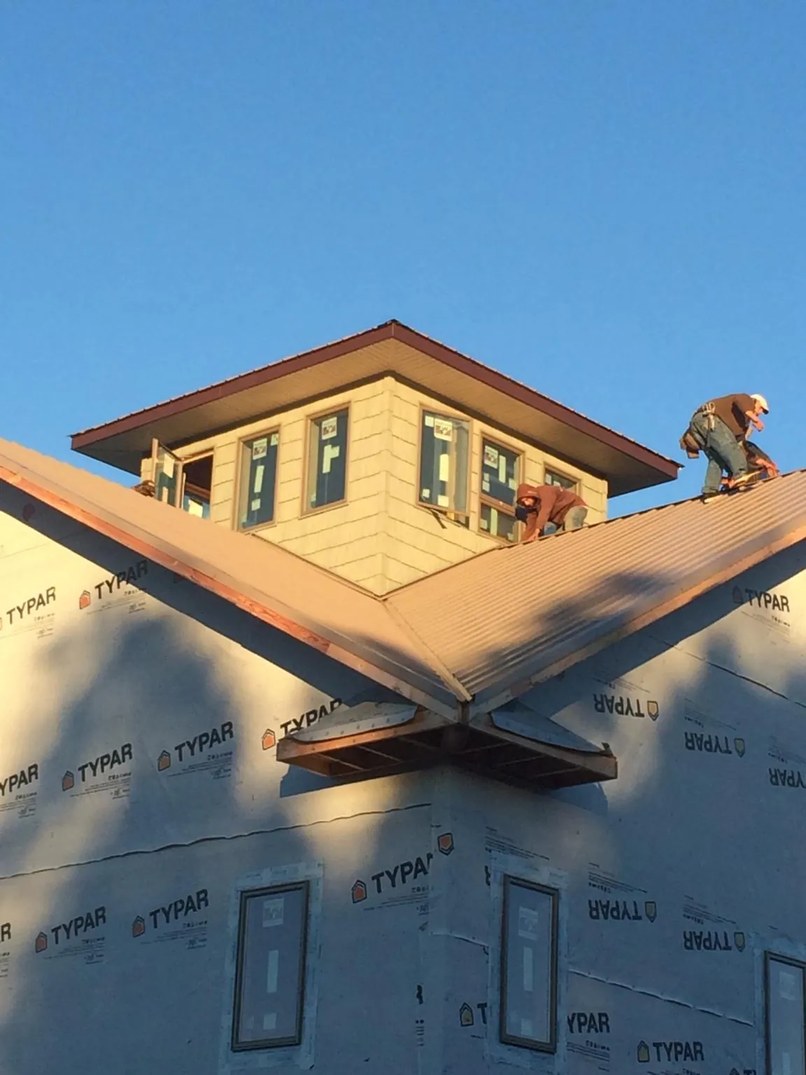 Roofers working around a rooftop cupola on a new metal roof at sunset — Roof Waterproofing in Piffard by Roofing Brothers